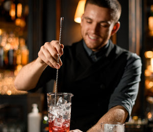 Bartender stirring a cocktail in a mixing glass with a bar spoon